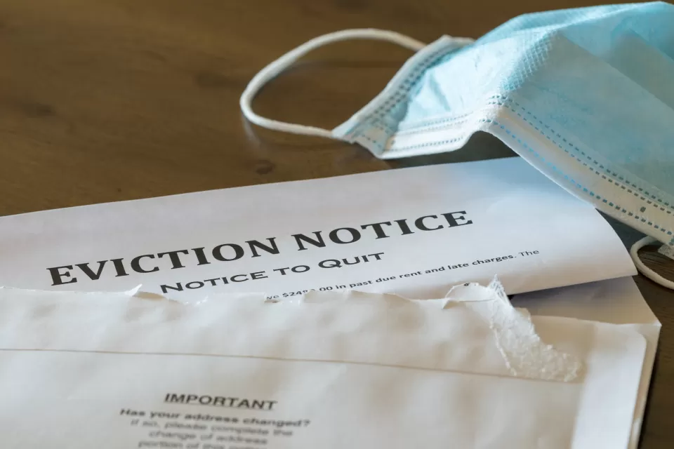 Eviction notice on table with surgical face mask lying next to it.